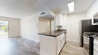 Located at 2235 W Broadway in Anaheim, CA, this single-story 2-bedroom, 2-bathroom residence offers a well-designed layout across a comfortable footprint. The open-concept living area seamlessly connects the kitchen, dining, and living spaces, creating an inviting and functional flow throughout. Wood-style plank flooring runs throughout the home, complementing the neutral color palette and textured ceilings.

The kitchen is a standout feature, showcasing white shaker cabinetry, dark countertops, a peninsula with a built-in sink, subway tile backsplash, and stainless steel appliances including a refrigerator, range, and microwave. A skylight above the kitchen provides an additional source of natural light. The living area opens directly to a private patio through sliding glass doors, offering outdoor views and an abundance of natural light.

The primary bedroom is generously sized and includes access to a walk-in closet with built-in shelving. Each bathroom is finished with white cabinetry, dark countertops, wood-style flooring, and a shower with sliding glass doors. A second closet provides additional storage. The clean, modern aesthetic and practical layout make this a well-appointed single-level home.