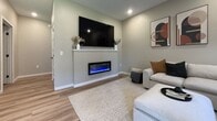This contemporary 990 square foot home in Rochester, Minnesota, offers a harmonious blend of style and functionality across two floors. The property features one spacious bedroom measuring 170 square feet, complemented by two well-designed bathrooms. The interior showcases a cohesive aesthetic with neutral tones and wood-look flooring throughout.

The kitchen boasts grey cabinetry, sleek black appliances, and a white subway tile backsplash, creating a modern and inviting cooking space. The living area is anchored by an electric fireplace with a mounted TV above, offering a cozy focal point. An office space provides a dedicated work area with a view.

The bedroom is generously sized with sliding glass doors leading to a balcony, flooding the space with natural light. Both bathrooms feature contemporary vanities and fixtures, with one including a tub-shower combination.

Additional amenities include a walk-in closet with ample storage, and an attached garage. The home's design prioritizes open spaces and natural light, creating an airy and welcoming atmosphere throughout. Located at 4871 Pines View Pl NW in Sage, this property combines modern living with practical design in a desirable Rochester neighborhood.