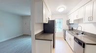 This single-floor residence offers a clean, modern aesthetic throughout its thoughtfully designed layout. The galley-style kitchen is a standout feature, showcasing white shaker cabinetry, dark countertops, and a full suite of stainless steel appliances including a refrigerator, range, microwave, and dishwasher. Light wood-style flooring runs through the kitchen and connects to the open living areas, lending warmth and continuity to the space.

The living area is bright and open, benefiting from natural light through large windows dressed with vertical blinds. A sliding glass door provides access to an outdoor area, further enhancing the sense of openness. A secondary living or dining space is also present, finished with the same light flooring and neutral wall tones.

The bedrooms are carpeted for comfort, each featuring textured ceilings and windows that allow in natural light. One bedroom includes a mirrored sliding-door closet, offering practical storage. The bathroom is well-appointed with white cabinetry, a dark countertop vanity, brushed nickel fixtures, a wall-mounted mirror, and a full tub-shower combination with tiled surround. A second bathroom features a similar vanity and a frosted window for privacy. Throughout, the neutral palette and updated finishes create a cohesive, move-in-ready environment.