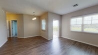 This single-floor space offers a thoughtfully designed open-concept layout that seamlessly connects the living, dining, and kitchen areas. Rich wood-look hard flooring flows throughout the main living spaces, complemented by neutral warm-toned walls and abundant natural light from multiple windows fitted with white blinds. A pendant light fixture anchors the dining area, while a door leads directly to a private balcony with pleasant outdoor views.

The kitchen serves as a central hub, featuring granite countertops, white shaker-style cabinetry, and a full suite of stainless steel appliances, including a range, microwave, and refrigerator. A breakfast bar peninsula provides additional workspace and casual seating. Adjacent to the kitchen is a walk-in pantry with wire shelving for generous storage, as well as a dishwasher conveniently integrated into the cabinetry.

The bedrooms are carpeted for comfort, each receiving natural light through windows with outdoor views. The bathroom is well-equipped with a tiled tub-shower combination, a white vanity, and granite countertops. A dedicated laundry area accommodates a full-size washer and dryer, adding everyday convenience to this functional and cohesive living space.