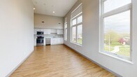 Located at 200 W First St in Cedar Falls, Iowa, this thoughtfully designed single-floor unit offers a bright, open-concept layout with soaring ceilings that create an impressive sense of vertical space throughout. Light wood-tone luxury vinyl plank flooring runs continuously across all living areas, complementing the neutral gray walls and white trim for a clean, modern aesthetic.

The open living and kitchen area is anchored by large multi-pane windows that flood the space with natural light and frame views of the surrounding Cedar Falls cityscape. The kitchen features white shaker-style cabinetry, light countertops, and a full suite of stainless steel appliances, including a refrigerator, electric range, over-the-range microwave, and dishwasher — all set against the dramatic backdrop of the tall ceilings.

The bedrooms are generously proportioned, each benefiting from tall ceilings and large windows with urban views. Track lighting in the secondary bedroom adds functional versatility.

The unit includes two full bathrooms, each finished with warm wood-toned vanity cabinetry, white countertops, a large vanity mirror with overhead lighting, a full tub/shower combination, and wood-look flooring. One bathroom is equipped with grab bars, offering added accessibility. Throughout, the design balances modern style with practical livability.