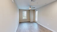 Located along N Loop 1604 E in San Antonio, TX, this thoughtfully designed 1-bedroom, 1-bathroom residence offers a clean, modern aesthetic throughout. The open-concept kitchen and living area serves as the heart of the home, showcasing a granite-topped peninsula with an undermount sink, gray shaker-style cabinetry, stainless steel appliances including a French door refrigerator, electric range, and built-in microwave, all set atop light-toned hardwood-style flooring that flows seamlessly through the main living spaces. A full-light exterior door in the living area invites natural light and provides outdoor access. The bedroom is a comfortable retreat featuring plush carpet, dual windows with blinds, a ceiling fan, and direct access to both the full bathroom and a closet. The bathroom is well-appointed with gray cabinetry, a granite vanity, a framed mirror with modern lighting, and a tiled tub-and-shower combination. Additional highlights include two closets, a dedicated laundry area, and carpeted stairway access. Neutral wall tones and clean white trim throughout create a bright, cohesive atmosphere that is both functional and inviting.