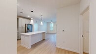 Located at 100 Wilton Cir S in Palm Coast, Florida, this thoughtfully designed single-story home offers two bedrooms, two bathrooms, and a practical, well-appointed layout. The open-concept kitchen serves as the heart of the home, featuring gray shaker-style cabinetry, a classic white subway tile backsplash, light quartz countertops, stainless steel appliances, and a central island with stylish pendant lighting overhead. The kitchen flows seamlessly into the living area, which is bathed in natural light from large windows and fitted with light wood-style luxury vinyl flooring. A dedicated pantry and in-unit laundry room add to the home's functional design. Both bedrooms are carpeted and equipped with ceiling fans, offering a comfortable and quiet retreat. The primary bedroom connects to a well-appointed en-suite bathroom featuring a dual-sink vanity with matte black hardware, wood-style flooring, and direct access to a spacious walk-in closet with wire shelving. The second bathroom mirrors the same clean, modern aesthetic. With five closets throughout, storage is abundant. The home's bright, neutral palette and modern finishes create a cohesive and welcoming ambiance throughout.