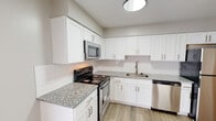 This well-appointed two-story home offers a thoughtfully updated interior with a consistent, modern aesthetic throughout both levels. The kitchen serves as a standout feature, showcasing crisp white shaker-style cabinetry, granite countertops with subtle speckled patterning, and a classic white subway tile backsplash. A full suite of stainless steel appliances — including a range, over-the-range microwave, dishwasher, and refrigerator — completes the space, all set atop wood-look flooring that extends seamlessly through the main living areas.

The open lower level is anchored by a staircase with a decorative white metal railing, connecting to the upper floor via carpeted steps. The airy, neutral-toned walls create a bright and welcoming atmosphere throughout. Bedrooms are generously sized with large windows that invite natural light, and include walk-in closet access for practical storage. Bathrooms are finished with white vanities, matte black hardware accents, and large mirrors, lending a clean and contemporary feel. A second bathroom on the upper level features a teal accent wall, adding a subtle pop of color. The overall design is cohesive, light-filled, and move-in ready.