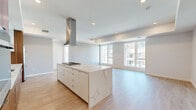 Located at 10375 Washington Blvd in the heart of Culver City, this modern 2-bedroom, 2-bathroom residence offers a thoughtfully designed open-concept layout with high-end finishes throughout. Light hardwood flooring flows seamlessly across the entire space, complementing the clean, contemporary aesthetic.

The kitchen is a standout feature, showcasing a striking combination of warm walnut cabinetry and high-gloss white upper cabinets, a bold marble-veined quartz backsplash, and matching quartz countertops. A large central island with a gas cooktop and stainless steel range hood serves as the focal point, while stainless steel appliances — including a side-by-side refrigerator and dishwasher — complete the chef-quality space. The kitchen opens directly into a spacious living area bathed in natural light from large windows.

The primary bedroom features a tray ceiling with warm ambient lighting, large sliding glass doors opening to a private balcony with open city views, and a dedicated closet. The second bedroom also benefits from generous windows and excellent natural light. Both bathrooms are finished with large-format neutral tiles and frameless glass walk-in showers, with the second bath featuring a dark stone vanity countertop. Two closets provide ample storage throughout the residence.