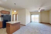 Located at 6120 NW 106th St in Johnston, Iowa, this well-appointed 3-bedroom, 2-bathroom single-story home offers a thoughtfully designed layout across a comfortable footprint. The open-concept living, dining, and kitchen area forms the heart of the home, where plush carpeting and a ceiling fan create a welcoming atmosphere. Sliding glass doors lead to a private balcony, bringing in natural light and pleasant outdoor views. The kitchen is well-equipped with warm wood cabinetry, black appliances including a range, microwave, dishwasher, and refrigerator, complemented by a central island with a light countertop — ideal for both cooking and casual dining. Pendant and overhead lighting add a functional finishing touch. The generously sized primary bedroom features its own ceiling fan and a walk-in closet with wire shelving for ample storage. Two additional bedrooms offer carpeted floors and windows that let in natural light. The home includes a dedicated in-unit laundry room with a full-size washer and dryer. Tile flooring accents the kitchen, bathrooms, and laundry areas, while carpet flows throughout the living spaces and bedrooms. Four closets throughout the home provide plentiful storage, rounding out this practical and comfortable Johnston residence.