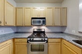 Located at 1200 N Herndon St in Arlington, VA, this two-story, 2-bedroom, 2-bathroom home offers a well-designed layout spread evenly across two floors. The main level welcomes you through a bright entrance with large windows and tiled flooring that transitions into warm light wood floors throughout. The open living and dining area is spacious and airy, with neutral tones and a staircase featuring classic wood railings leading to the upper floor. The kitchen is well-appointed with light maple cabinetry, granite-style countertops, stainless steel appliances including a gas range, built-in microwave, and dishwasher, offering ample storage and prep space. Upstairs, the bedrooms are generously sized, each with light wood flooring and large windows that invite natural light and outdoor views of the surrounding neighborhood. The primary bedroom includes a double-door closet for convenient storage. Both bathrooms are clean and functional, with one featuring a soaking tub and shower combination with white subway tile surround and mosaic tile flooring. Additional highlights include in-unit laundry, multiple closets throughout, a hallway, and two staircases for practical flow between floors.