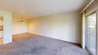 Located at 3307 Columbus Ave in Sandusky, Ohio, this single-floor, 2-bedroom, 2-bathroom home offers a functional and comfortable layout. The combined kitchen and living area forms the heart of the home, with the kitchen featuring white cabinetry, granite countertops, a stainless steel sink, tile flooring, recessed lighting, and white appliances including a refrigerator, range, microwave, and dishwasher. A pass-through opening connects the kitchen to the carpeted living room, which is brightened by large sliding glass doors that open to an outdoor view of the surrounding greenery, filling the space with natural light. Both bedrooms are carpeted and feature textured ceilings and windows that look out onto the landscaped exterior, providing a quiet, natural setting. The primary bedroom is generously sized and includes a closet with a wooden door. The two bathrooms are well-appointed, each with white fixtures; one features a granite-topped vanity with white cabinetry, a large mirror with pendant lighting, and a separate tub and shower room with tile flooring. The other includes a tub/shower combo with grab bars and a handheld showerhead. Neutral tones and carpet throughout the living spaces create a warm, cohesive ambiance.