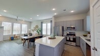 This well-designed two-story home offers a thoughtful layout with contemporary finishes throughout. The open-concept main living area seamlessly connects the kitchen, dining, and living spaces, creating a bright and functional hub for daily life. The kitchen is equipped with gray shaker-style cabinetry, white quartz countertops, stainless steel appliances including a gas range and refrigerator, a subway tile backsplash, and a central island with bar seating. Light wood-style flooring flows through the main level, complementing the neutral color palette. The dining area provides ample space for a full-size table, while the living room features large windows that invite natural light and a cozy, curated atmosphere. A convenient half bath with marble-look tile flooring and a pedestal sink is also found on this level. Upstairs, the welcoming entryway landing features a stylish console and staircase access. The bedrooms are comfortable and well-lit, with ceiling fans and recessed lighting. A dedicated home office with a window offers a quiet workspace. The full bathroom impresses with a gray vanity, white quartz countertop, marble-look tile flooring, and a glass-enclosed shower with elegant stone-look wall tile. Throughout, the home maintains a clean, modern aesthetic with warm, inviting touches.