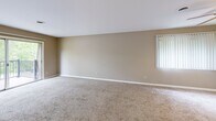 Located at 111 W Taylor St in Chesterton, Indiana, this two-bedroom, two-bathroom residence offers a functional and comfortable single-floor layout. The combined kitchen and living area serves as the heart of the home, with the kitchen featuring a drop ceiling with panel lighting, warm wood-toned cabinetry, tile flooring, and a pass-through counter that opens to the living space. The spacious living room is carpeted and receives natural light through a vertical-blind-covered window, with sliding door access leading to an outdoor area. Both bedrooms are carpeted and fitted with ceiling fans, neutral-toned walls, and generous closet storage via full-wall bifold doors. The primary bedroom is notably spacious with ample room for furnishings. Each bathroom is cleanly appointed — one features a wood-framed vanity mirror and single-basin sink, while the other includes a full tiled tub-shower combination. Textured walls add subtle character throughout the unit. A connecting hallway ties the layout together efficiently, and windows in the bedrooms frame views of the surrounding greenery, lending a calm, natural quality to the interior ambiance.