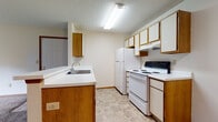 Located at 3675 Cross Ridge Ln in Canal Winchester, Ohio, this single-floor unit offers a practical and functional layout designed for comfortable everyday living. The open-concept living and kitchen area forms the heart of the space, where a peninsula countertop with an integrated sink separates the kitchen from the carpeted living area. The kitchen is equipped with white appliances including a refrigerator and electric range, ample upper and lower cabinetry with warm wood-toned accents, and tile-style flooring beneath. A ceiling fan in the main living area aids in air circulation, while a sliding glass door fitted with vertical blinds fills the room with natural light and provides access to the outdoors, offering views of the surrounding greenery. The bedrooms are carpeted and well-proportioned, each featuring neutral walls, natural light from windows, and access to closet storage. The full bathroom includes a single-sink vanity with a large mirror, a toilet, and a tub-shower combination, all finished in clean, neutral tones with tile-style flooring. Textured ceilings are consistent throughout the unit. The overall layout is efficient and straightforward, making this a well-organized space suited for a variety of living arrangements.