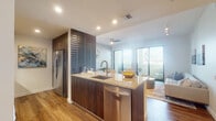 Located at 211 S Dixie Hwy in Coral Gables, Florida, this single-floor residence showcases a contemporary design with high-quality finishes throughout. The open-concept layout seamlessly connects the kitchen, dining, and living areas, creating a cohesive and functional living space bathed in natural light.

The kitchen is a standout feature, equipped with rich dark-wood cabinetry, granite countertops, a textured tile backsplash, and stainless steel appliances including a refrigerator, dishwasher, range, and built-in microwave. A central island with an undermount sink serves as both a prep station and casual gathering point.

The living area extends toward floor-to-ceiling sliding glass doors that open onto a private balcony, offering open views of the Coral Gables skyline. Wide-plank wood flooring flows throughout the main living spaces, enhancing warmth and continuity.

The bedroom features wood flooring, a ceiling fan, ample closet space, and a bright window with natural light. The bathrooms are finished with large-format marble-style tile flooring, dark wood vanities topped with granite, and backlit mirrors that provide an elegant, spa-like ambiance.

A dedicated dining area with neutral tones and contemporary décor completes this well-appointed residence.