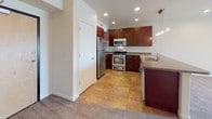 This single-story unit offers a thoughtfully designed layout that balances open communal spaces with private living areas. The open-concept living room is generously sized, featuring neutral-toned wall-to-wall carpeting, recessed lighting, and a sliding glass door that invites natural light and provides outdoor views. The space flows seamlessly into the kitchen, which is equipped with rich, dark-cherry cabinetry, stainless steel appliances including a gas range, microwave, and refrigerator, as well as a double sink and tile flooring. A breakfast bar adds convenient casual dining space at the kitchen's edge.

The bedrooms are carpeted and well-lit, each featuring ceiling fans, window blinds for light control, and ample wall space. The bathrooms are finished with coordinating dark-cherry cabinetry. The primary bathroom showcases a wide double-sink vanity with a dark countertop, large mirrors, and tile flooring. A secondary bathroom features a full soaking tub with a tiled shower surround and chrome fixtures. Throughout the unit, neutral tones and consistent finishes create a cohesive, clean aesthetic.