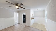 Located in Hanahan, South Carolina, this efficient one-bedroom, one-bathroom unit offers a well-organized single-floor layout that makes smart use of every square foot. The floor plan connects each functional space in a logical and accessible flow, as seen in the dollhouse overview.

The kitchen is designed as a galley-style corridor, featuring light wood-look luxury vinyl flooring, white cabinetry, granite-look countertops with a stainless steel sink, and black appliances including a refrigerator and electric range. Exposed painted brick accents on both sides of the kitchen entry add a distinctive architectural detail that gives the space character.

The bedroom is a comfortable, well-proportioned room finished with soft wall-to-wall carpeting and neutral gray walls. A ceiling fan with a light fixture provides both air circulation and overhead lighting. A wall-mounted HVAC unit ensures climate control, and a window allows for natural light to enter the space.

The bathroom is clean and functional, equipped with a full-size tub and shower combination featuring a bright white surround and chrome fixtures. The overall palette throughout the unit remains light and neutral, creating a cohesive and easy-to-customize living environment. This unit is well-suited for individuals or couples seeking a straightforward, low-maintenance living space in the Hanahan area.