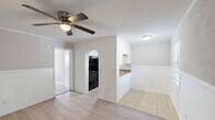 Located in Hanahan, South Carolina, this efficient one-bedroom, one-bathroom unit offers a well-organized single-floor layout that makes smart use of every square foot. The floor plan connects each functional space in a logical and accessible flow, as seen in the dollhouse overview.

The kitchen is designed as a galley-style corridor, featuring light wood-look luxury vinyl flooring, white cabinetry, granite-look countertops with a stainless steel sink, and black appliances including a refrigerator and electric range. Exposed painted brick accents on both sides of the kitchen entry add a distinctive architectural detail that gives the space character.

The bedroom is a comfortable, well-proportioned room finished with soft wall-to-wall carpeting and neutral gray walls. A ceiling fan with a light fixture provides both air circulation and overhead lighting. A wall-mounted HVAC unit ensures climate control, and a window allows for natural light to enter the space.

The bathroom is clean and functional, equipped with a full-size tub and shower combination featuring a bright white surround and chrome fixtures. The overall palette throughout the unit remains light and neutral, creating a cohesive and easy-to-customize living environment. This unit is well-suited for individuals or couples seeking a straightforward, low-maintenance living space in the Hanahan area.