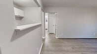 Located at 3583 Alaska Ave in Cincinnati, Ohio, this single-level one-bedroom, one-bathroom unit offers a clean, modern aesthetic achieved through fresh neutral gray paint, crisp white trim, and consistent wood-look laminate flooring throughout. The layout is efficiently organized, connecting each room through a central hallway that provides a logical flow across the space.

The living area is bright and open, featuring a wall-mounted air conditioning unit and a baseboard heating system, with natural light filtering in through a window fitted with blinds. The kitchen is thoughtfully appointed with white cabinetry, granite-look countertops, a stainless steel single-basin sink, and upper cabinets offering practical storage. A half-wall peninsula detail adds architectural interest while separating the kitchen from the main living area.

The bedroom is a comfortably sized retreat with neutral gray walls, wood-look flooring, a window with blinds for natural light and privacy, and a baseboard heater. The bathroom is finished in a clean, classic style, featuring a full-size bathtub with a tiled surround in white, complemented by chrome fixtures. A white vanity with storage completes the bathroom.

Overall, the space presents a cohesive, move-in-ready environment with a clean, minimalist character well-suited for straightforward, comfortable single-occupant living.