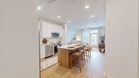 Located at 23615 Kingsland Blvd in Houston's Katy area, this one-bedroom, one-bathroom residence offers a thoughtfully designed layout across a single floor. Light wood flooring flows throughout, creating a warm and cohesive aesthetic.

The open-concept kitchen and living area serves as the heart of the home. The kitchen is outfitted with white shaker cabinetry accented by gold hardware, open shelving, a white quartz countertop, and a full suite of stainless steel appliances including a French door refrigerator, dishwasher, microwave, and range. A wood-paneled kitchen island with seating for two provides a casual dining option and additional prep space.

The living room is bright and airy, with large windows and a glass door that invite natural light and offer outdoor views. A ceiling fan adds comfort to the space.

The bedroom is a serene retreat, featuring a generously sized window, a ceiling fan, and direct access to a dedicated closet with built-in shelving and dual hanging rods for organized storage.

The bathroom is elegantly finished in an all-white palette, featuring a full soaking tub with tile surround, a long single-sink vanity with gold hardware, an illuminated mirror, and light wood flooring that ties the design together seamlessly.