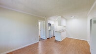 Located at 3280 Blue Ridge Circle in Stockton, California, this one-bedroom, one-bathroom unit offers a functional and efficiently designed single-floor layout. The combined kitchen and living area forms the heart of the home, featuring warm hardwood-style flooring, crown molding, and a textured ceiling throughout. A large window alongside the front entry door fills the living space with natural light and offers views of surrounding greenery, while a wall-mounted AC unit ensures year-round comfort. The kitchen is positioned at the rear of the living area and features white cabinetry, a gas range, refrigerator, microwave, and a peninsula with a double-basin sink and tile countertops — providing both storage and a convenient workspace. A wall heater is also present for supplemental warmth. The bedroom is a well-proportioned, carpeted retreat with its own window overlooking the outdoors and includes access to a dedicated closet. The bathroom is clean and practical, equipped with a single-sink vanity with tile countertops, a toilet, and a full tub/shower combination enclosed by sliding glass doors, set on hardwood-style flooring. The unit's straightforward layout and included appliances make it a practical and comfortable living space.