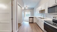 Located at The Elements in Rapid City, South Dakota, this single-floor residence offers a thoughtfully designed layout with modern finishes throughout. The kitchen is a standout feature, outfitted with crisp white shaker-style cabinetry, black hardware accents, light-toned countertops, and a full suite of stainless steel appliances including a refrigerator, range, over-the-range microwave, and dishwasher. A double-basin sink and generous cabinet storage make the space highly functional. Durable wood-look flooring runs through the kitchen and main living areas, lending a clean, contemporary aesthetic. The living area is illuminated by a ceiling fan and benefits from a sliding glass door that opens to a private balcony, allowing natural light to fill the space. The bedroom features plush carpet flooring and a spacious closet with bifold doors and a full-width hanging rod, providing ample storage. The bathroom is finished with wood-look flooring, a full tub-shower combination, and clean, neutral wall tones that contribute to a bright and functional space. Overall, the unit presents a fresh, move-in-ready environment with a cohesive modern design palette suited for comfortable everyday living.