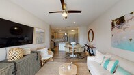 Located at 4645 Gordon Rd in Wilmington, NC, this single-floor residence offers a thoughtfully designed open-concept layout with a coastal-inspired aesthetic throughout. The living area is bright and welcoming, featuring wood-style flooring, a ceiling fan, and sliding glass doors that open to a private balcony overlooking lush outdoor scenery, filling the space with natural light.

The kitchen is a standout feature, outfitted with gray shaker-style cabinetry, granite countertops, a white subway tile backsplash, stainless steel appliances, and a central island with an undermount sink and pendant lighting overhead. A dining area connects seamlessly to both the kitchen and living room, reinforcing the open flow of the space.

Two generously sized bedrooms each feature plush carpeting and ceiling fans. The primary bedroom is a serene retreat with ample space, while the second bedroom offers natural light through window treatments. Both bathrooms are well-appointed with wood-style flooring, granite vanity countertops, and gray cabinetry. One bathroom includes a walk-in glass-enclosed shower with built-in shelving. The neutral color palette and coastal décor accents throughout create a calm, cohesive ambiance ideal for comfortable living.