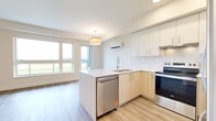 Located at 7701 E Saanich Rd in Saanichton, BC, this well-appointed one-bedroom, one-bathroom unit offers a thoughtfully designed single-floor layout with a clean, contemporary aesthetic throughout. The open-concept living and kitchen area serves as the heart of the home, featuring a two-tone cabinetry scheme — crisp white uppers paired with light wood lowers — complemented by a white quartz countertop and a peninsula island ideal for casual dining or food preparation. Stainless steel appliances, including a fridge, electric range, and built-in microwave hood fan, complete the modern kitchen. Light wood-tone vinyl plank flooring flows seamlessly throughout the entire unit, enhancing the bright and airy atmosphere created by recessed pot lighting and a wall-mounted mini-split system. The bedroom is a serene retreat, benefiting from a large window that frames open green field views, a built-in baseboard heater, and a spacious sliding-door closet. The full bathroom is finished to a high standard, offering a sliding glass tub-shower enclosure, a vanity with quartz countertop, and matching cabinetry. The overall ambiance is calm, clean, and move-in ready.