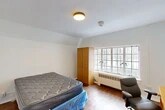Located at 800 University Ave in Ithaca, NY, this single-occupancy room offers a straightforward and functional layout well-suited for student or individual living. The room features warm hardwood-style flooring throughout, which adds a touch of character to the otherwise clean, white-walled interior. A prominent multi-pane window along one wall allows natural light to filter into the space while offering views of the surrounding trees, giving the room an airy and connected-to-nature feel. Beneath the window sits a radiator heating unit, ensuring comfort during Ithaca's cold seasons. A tall, wood-toned wardrobe cabinet provides dedicated storage, complementing the room's efficient use of space. The angled ceiling detail near one wall adds a subtle architectural element to the otherwise simple design. Ceiling-mounted lighting provides consistent illumination throughout the room. A solid dark-painted entry door offers privacy and a clear separation from surrounding areas. The room is designed with functionality in mind, providing enough space to accommodate a bed, desk, and seating, making it a practical option for individuals seeking a straightforward living arrangement near the University Ave corridor in Ithaca.