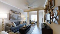 Located at 45 Lullwater Dr in Richmond Hill, Georgia, this single-story residence offers a thoughtfully designed layout with refined interior details and a welcoming ambiance. The living area serves as the heart of the home, showcasing elegant crown molding, decorative columns, and smooth ceilings accented by a ceiling fan — details that lend a sense of architectural character and craftsmanship. The space flows seamlessly into a secondary sitting area, defined by the columned divide, allowing for flexible use of the open floor plan. Large windows dressed with sheer curtains invite an abundance of natural light, creating a bright and airy atmosphere throughout. The hard-surface flooring adds both durability and visual continuity across the living spaces. Neutral wall tones paired with warm accent lighting contribute to a comfortable and polished aesthetic. Wall art and curated décor elements enhance the overall sense of style, reflecting a home that balances practicality with thoughtful design. The single-floor layout ensures ease of access and convenient living throughout, making this Richmond Hill property a well-appointed and inviting place to call home.