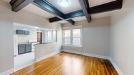 Located at 525 Greenup St in Covington, Kentucky, this one-bedroom, one-bathroom residence offers a well-organized single-floor layout across a comfortable footprint. The living room immediately impresses with its striking dark coffered ceiling beams, warm hardwood floors, and natural light streaming through double-hung windows that overlook the surrounding neighborhood. An open pass-through connects the living area to the kitchen, enhancing the sense of flow throughout the space.

The kitchen is thoughtfully appointed with gray cabinetry, granite-style countertops, a gas range, refrigerator, and a stainless steel sink beneath a bright double window. Marble-look tile flooring adds a clean, modern contrast to the classic character found elsewhere in the home. A separate den provides additional flexible living space.

The spacious primary bedroom features rich hardwood floors, a ceiling fan, and generous natural light through large windows with neighborhood views. The den area also benefits from the same handsome exposed beam detailing seen in the living room. A long hallway connects the rooms efficiently, complemented by three closets for ample storage. The full bathroom is clean and functional, offering a tub-shower combination, vanity, and tile flooring. This residence blends historic architectural charm with updated finishes throughout.