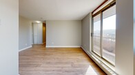 Located on the 15th floor at 235 Rebecca Street in Hamilton, Ontario, this one-bedroom, one-bathroom unit offers a compact yet efficiently designed layout. Light wood laminate flooring runs throughout, complementing the neutral grey and white tones of the walls and trim to create a clean, cohesive aesthetic.

The combined living and dining area is the heart of the unit, featuring large sliding glass doors and expansive windows that flood the space with natural light and frame sweeping views of the Hamilton cityscape. Baseboard heating runs along the perimeter, and a textured ceiling adds a subtle architectural detail.

The bedroom is a comfortable and private retreat, benefiting from its own large window with city views and continued wood-tone flooring. Natural light pours in throughout the day, making the room feel bright and airy.

The kitchen is positioned adjacent to the living area, offering a practical, self-contained cooking space with white cabinetry visible from the open-plan layout. The bathroom is neatly tucked away, completing the unit's functional floor plan.

Overall, the unit presents a bright, move-in-ready space with a straightforward layout, quality natural light, and elevated city views — well suited for those seeking a practical urban residence in downtown Hamilton.
