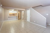 Located at 11 N Stonecrest Ct in Hobbs, New Mexico, this two-story home offers a practical and functional layout spread across two levels. The main living area greets residents with large-format tile flooring and neutral gray walls, creating a clean and understated aesthetic. A staircase runs along one wall, contributing architectural interest to the space. A tiled fireplace with a sleek surround serves as a focal point in the living room, accompanied by a window that draws in natural light.

The kitchen is accessible via a pass-through counter that opens to the living and dining area, promoting an open-concept feel. It is equipped with white cabinetry extending to the ceiling, white appliances including a refrigerator, electric range, built-in microwave, and dishwasher, alongside a double stainless steel sink and light countertops. Tile flooring continues throughout the kitchen for easy maintenance.

The upper level houses the bedrooms, each featuring warm carpet flooring, neutral walls, and ceiling fans with integrated lighting. Windows allow natural light into the bedrooms. The bathroom includes tile flooring, a tiled tub-shower combination, a white vanity, and matching fixtures, offering a straightforward and clean design throughout.