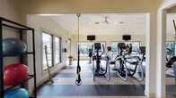 This single-story fitness and amenity facility offers a thoughtfully designed space that blends coastal charm with modern functionality. The welcoming lobby sets the tone with a striking Jacksonville Beach Fishing Pier mural as a focal point, complemented by rich herringbone-patterned hardwood flooring, globe pendant lighting, and elegant glass-top furniture. Tall tropical plants and framed artwork add warmth, while a built-in shelving unit with a granite-topped counter provides a polished, organized reception area.

Transitioning from the lobby, the fitness center is generously proportioned and bathed in natural light through large picture windows that frame views of palm trees and a sparkling outdoor pool. The workout area is outfitted with a full array of cardio equipment, including treadmills, elliptical trainers, and stationary bikes, all featuring individual screens. A TRX suspension training system hangs from the ceiling, while a mirrored wall expands the sense of space and supports strength training. Ceiling fans maintain airflow throughout, and wall-mounted flat-screen televisions add entertainment options. The durable, easy-to-maintain flooring is designed for high-traffic athletic use, and ample natural light creates an energizing atmosphere conducive to an active lifestyle.