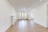 Located at 5235 Chemin de la Côte-Saint-Luc in Montréal, this well-appointed 1-bedroom, 1-bathroom unit offers a thoughtfully designed single-floor layout. The expansive living area immediately impresses with its crisp white walls, decorative wainscoting panel moldings, and a stunning ornamental fireplace with an arched surround — a classic architectural detail that anchors the room. Light hardwood flooring runs throughout, complementing the bright, airy atmosphere created by multiple windows that invite generous natural light. Recessed lighting adds a modern touch overhead. A secondary living space provides additional flexibility for dining or lounging. The galley-style kitchen is outfitted with sleek white cabinetry, white quartz countertops, stainless steel appliances including a refrigerator and range, and a window framed by navy curtains. The spacious primary bedroom features large windows with leafy outdoor views and connects to two closets, offering ample storage. A second room with decorative wall moldings serves as an additional living or flex space. The bathroom is finished with dark slate-style floor tiles, a clean white vanity, and a tub-shower combination with full tile surround. A welcoming hallway completes this bright, move-in-ready Montréal home.