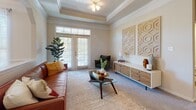 This single-floor residence offers a thoughtfully designed layout that balances comfort and functionality across multiple well-defined living spaces. The living room is a standout, featuring an elegant tray ceiling with crown molding detail, carpeted flooring, and French doors that invite natural light while providing outdoor access. Adjacent to the living area, the dining room continues the refined aesthetic with wainscoting panels, crown molding, and a modern sputnik-style chandelier overhead, all bathed in natural light from a large window with sheer curtains.

The kitchen is designed for practicality and style, showcasing dark granite countertops, a breakfast bar, white cabinetry, a stainless steel refrigerator, and a full suite of appliances. The space flows seamlessly into the main living areas, making it ideal for everyday use.

The primary bedroom is generously sized, featuring plush carpeting, large windows that fill the room with natural light, and ample space for a full furniture arrangement. The primary bathroom includes a wide dual-sink vanity with white cabinetry and an expansive mirror. The secondary bedroom is equally comfortable and well-lit. A second full bathroom with a single-sink vanity and shower-tub combination completes the layout, offering convenience for guests or additional occupants.