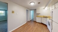 Located at 1717 Kuntz Rd in Erie, Pennsylvania, this two-bedroom, one-bathroom unit offers a practical and efficiently designed single-floor layout. The kitchen is a functional space equipped with white cabinetry, warm wood-tone countertops, a full suite of white appliances including an electric range, dishwasher, and refrigerator, and a stainless steel sink. The kitchen opens toward a hallway that connects the main living areas, with durable hardwood-style flooring running throughout the common spaces. Both bedrooms feature neutral-toned carpet and soft gray walls, creating a calm and versatile environment. The primary bedroom is generously proportioned and receives natural light through a window with an outdoor view of surrounding greenery. The second bedroom is similarly configured, also featuring a window that brings in natural daylight. The bathroom is clean and simply appointed, with a tub and shower combination, a white vanity with storage, a toilet, and hardwood-style flooring that complements the rest of the unit. Textured ceilings are present throughout the space, and consistent neutral wall tones contribute to a cohesive, understated aesthetic. The layout is compact yet thoughtfully organized, making efficient use of every square foot.