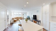 Located at 195 Mansfield Ave in Norton, MA, this well-designed 2-bedroom, 2-bathroom single-floor home offers a bright and modern living experience. The open-concept layout seamlessly connects the kitchen, dining, and living areas, creating a spacious and functional common space. The kitchen is a standout feature, equipped with white shaker cabinetry extending to the ceiling, stainless steel appliances including a gas range, built-in microwave, and refrigerator, along with a large central island with quartz countertops that doubles as a dining and prep area. Recessed lighting and warm hardwood flooring throughout the main living space add to the clean, contemporary aesthetic. The living room is generously sized, with large windows allowing abundant natural light to fill the room. The primary bedroom offers a comfortable, carpet-floored retreat with multiple windows and ample closet space. Both bathrooms are well-appointed; the primary bathroom features a double-sink vanity with white shaker cabinetry, dual mirrors, and classic black-and-white mosaic tile flooring, while the second bathroom mirrors a similarly clean design. Two dedicated closets provide additional storage throughout the home.