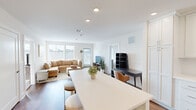 Located at 195 Mansfield Ave in Norton, MA, this well-designed 2-bedroom, 2-bathroom single-floor home offers a bright and modern living experience. The open-concept layout seamlessly connects the kitchen, dining, and living areas, creating a spacious and functional common space. The kitchen is a standout feature, equipped with white shaker cabinetry extending to the ceiling, stainless steel appliances including a gas range, built-in microwave, and refrigerator, along with a large central island with quartz countertops that doubles as a dining and prep area. Recessed lighting and warm hardwood flooring throughout the main living space add to the clean, contemporary aesthetic. The living room is generously sized, with large windows allowing abundant natural light to fill the room. The primary bedroom offers a comfortable, carpet-floored retreat with multiple windows and ample closet space. Both bathrooms are well-appointed; the primary bathroom features a double-sink vanity with white shaker cabinetry, dual mirrors, and classic black-and-white mosaic tile flooring, while the second bathroom mirrors a similarly clean design. Two dedicated closets provide additional storage throughout the home.