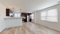 This well-appointed single-floor space combines modern finishes with a clean, functional layout. The kitchen is a standout feature, showcasing rich dark espresso cabinetry, light granite countertops, and a classic white subway tile backsplash. Stainless steel appliances — including a gas range, microwave, refrigerator, and dishwasher — complete the kitchen's polished look. A peninsula with pendant lighting adds a stylish focal point while providing additional counter space and an open connection to the living area. Light hardwood-style flooring flows seamlessly throughout the space, creating a bright and cohesive atmosphere. The open-concept living area benefits from multiple windows that invite natural light, offering an airy and welcoming ambiance. The bedrooms are thoughtfully designed with clean white walls, light flooring, and ample closet space, providing a calm and comfortable retreat. The bathroom features a full tub and shower combination, fully clad in white subway tile, lending a crisp and timeless aesthetic. Throughout the unit, white trim, recessed lighting, and neutral tones contribute to a fresh, move-in-ready environment that is both functional and visually appealing.