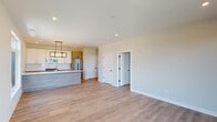 This thoughtfully designed single-floor residence combines contemporary style with functional living. The open-concept layout connects the living area to the kitchen, creating a seamless flow ideal for everyday living and entertaining. Light hardwood flooring runs throughout, lending warmth and continuity to each space.

The kitchen is a standout feature, anchored by a generous island with a light stone countertop and an undermount sink, clad in a sleek linear tile finish. Upper cabinetry is finished in crisp white, complemented by warm wood-toned lower cabinets and a classic white subway tile backsplash. Stainless steel appliances — including a gas range, built-in microwave, and French door refrigerator — complete the well-appointed setup. A striking geometric pendant light fixture adds a bold, modern accent above the island.

The living area is bathed in natural light through large windows that frame views of the surrounding neighborhood. Recessed lighting throughout ensures consistent illumination in every corner. A door leads to a private balcony, extending the living space outdoors.

The bathroom is finished with clean, neutral tones, featuring a white undermount vanity sink, chrome fixtures, a large mirror with overhead lighting, and a tiled shower area. Additional rooms offer flexible space, all maintaining the same light, airy aesthetic found throughout this well-crafted residence.