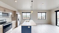 Located at 1 Main St in Menasha, WI, this modern 2-bedroom, 2-bathroom residence offers a well-designed single-floor layout with contemporary finishes throughout. The open-concept kitchen and living area serves as the heart of the home, anchored by a striking navy blue kitchen island with a white quartz countertop, undermount sink, and pendant lighting. Light wood cabinetry, stainless steel appliances — including a French door refrigerator, electric range, and built-in microwave — complete the functional and stylish kitchen. Large black-framed windows flood the space with natural light and offer views of the surrounding Menasha neighborhood. Light wood-look flooring extends throughout the main living areas, creating a clean, cohesive aesthetic. The primary bedroom features sliding glass door access to an outdoor area and ample natural light, while the second bedroom is finished with soft carpeting and neutral walls. Both bathrooms are outfitted with tub-shower combinations, modern vanities with white countertops, and matte black fixtures and hardware. The overall design palette of warm neutrals, matte black accents, and light wood tones gives the space a fresh, contemporary character well-suited for modern living.