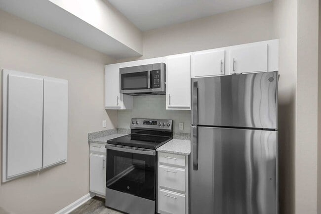 Kitchen with stainless steel appliances, white cabinetry, electric range, microwave, and compact layout with overhead storage - Parham Pointe