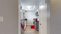 This single-story residence in Fremont, California presents a well-organized layout with a cohesive design aesthetic characterized by soft blue-gray walls, crisp white trim, and crown molding throughout. Wood-look flooring flows through the main living areas, while plush carpeting adds comfort to the bedrooms.

The kitchen is efficiently designed with a galley-style configuration, featuring white cabinetry, dark granite-style countertops, stainless steel appliances, and a recessed tray ceiling with overhead lighting. A peninsula counter with a pass-through opening connects the kitchen to the adjacent living area, enhancing the sense of openness and facilitating easy interaction between spaces.

The living area is bright and open, with sliding glass doors that lead to a private balcony overlooking the surrounding neighborhood. A low built-in shelving unit near the entry adds a functional architectural detail to the space.

The bedrooms are carpeted and well-proportioned, each featuring crown molding and windows that allow natural light. One bedroom includes a sliding closet with built-in shelving, while an additional bedroom provides convenient access to a bathroom. The overall layout, as seen in the 3D floor plan, is compact yet functional, making efficient use of the available space.