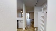 This single-floor studio unit offers a thoughtfully designed open layout that maximizes every square foot of available space. The interior features durable wood-look plank flooring that flows seamlessly throughout the main living areas, lending a warm and cohesive aesthetic. The kitchen is efficiently arranged with white cabinetry, light countertops, and stainless steel appliances, opening toward the living space to create a connected, airy feel. A structural column adds a subtle architectural element that defines the transition between the kitchen and living areas without interrupting the open concept. The living area is bright and inviting, highlighted by a sliding glass door that draws in natural light and provides a direct view of the outdoors. A ceiling fan overhead ensures comfortable airflow year-round. A textured ceiling adds depth to the interior finish. Built-in open shelving provides convenient and accessible storage, a practical feature that adds both function and visual interest. The bathroom completes the unit, offering a clean and functional space. Overall, this studio presents a well-organized, move-in-ready layout suited for efficient, comfortable living.