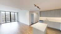 This well-appointed 2-bedroom, 2-bathroom residence offers a thoughtfully designed single-floor layout that balances modern aesthetics with functional living. The open-concept kitchen and living area serves as the heart of the home, featuring warm hardwood-style flooring, sleek light wood cabinetry extending to the ceiling, white quartz countertops, stainless steel appliances, a built-in wine cooler, and a central island perfect for dining or entertaining. The living room is flooded with natural light through expansive floor-to-ceiling sliding glass doors that open to a private balcony, offering stunning views of a resort-style courtyard complete with a pool, palm trees, and lush greenery. Both bedrooms are carpeted for comfort and include ceiling fans and dedicated closets. The primary bathroom is outfitted with a double-sink vanity topped with quartz counters, light wood cabinetry, and dual backlit mirrors, while the second bathroom features a similarly refined single-vanity design. Clean white walls, crisp trim, and consistent modern finishes throughout create a bright, cohesive ambiance that is both sophisticated and inviting.
