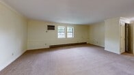 Located at 65 E Washington St in North Attleboro, MA, this single-floor unit offers a well-organized layout with a variety of thoughtfully finished spaces. The living and dining area features plush carpeting, crown molding, and a chandelier over the entry foyer, which transitions to hardwood flooring — creating a warm and welcoming atmosphere. Natural light filters in through multiple windows throughout the unit, complementing the soft, neutral yellow-toned walls.

The kitchen is equipped with stainless steel appliances, including an electric range and over-the-range microwave, set against dark granite countertops and a stone tile backsplash. Light wood cabinetry provides ample storage, while hardwood flooring ties the space together.

The bedrooms are generously sized with soft carpeting, baseboard heating, wall-unit air conditioning, and natural light from double-pane windows. Each bedroom includes closet space with built-in rods and shelving. The bathrooms are finished with white subway tile wainscoting, an accent mosaic tile border, dark granite vanity tops, light wood cabinetry, and tile flooring — offering a clean, modern aesthetic. The overall layout is functional and cohesive, making this a comfortable and move-in-ready space.