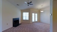 This single-story home at 6350 301 offers a welcoming and well-designed living space. The main living area is a standout feature, characterized by soaring vaulted ceilings that create a sense of openness and volume. A ceiling fan is centrally mounted, providing both function and a finishing architectural touch to the room.

Natural light flows generously into the space through a large window and a set of French doors, which also provide access to the outdoors. The French doors allow views to the exterior, enhancing the connection between inside and outside. A pendant light fixture near the doors adds a warm, decorative element to the space.

The living area features a classic fireplace with a dark surround and hearth, serving as a natural focal point and offering a cozy gathering spot. The room is finished with neutral-toned carpeting throughout, complementing the light-colored walls and contributing to the overall calm, understated aesthetic.

The combination of vaulted ceilings, abundant natural light, and thoughtful design details gives this home a comfortable and inviting ambiance suited to everyday living.