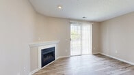 Located in Cranberry Township, PA, this well-appointed 3-bedroom, 2-bathroom residence offers a thoughtfully designed single-floor layout ideal for comfortable everyday living. The open-concept kitchen is a functional highlight, featuring crisp white shaker cabinetry, light quartz countertops, a peninsula with an undermount sink, and a full suite of stainless steel appliances including a refrigerator, gas range, microwave, and dishwasher. Light wood-look flooring runs throughout the main living areas, contributing to a bright and cohesive aesthetic. The spacious living room is anchored by a classic fireplace with a white mantel and includes a sliding glass door that invites natural light and provides access to the outdoors. A decorative column subtly defines the entry area. The generously sized primary bedroom features plush carpeting, a large closet with sliding doors, a walk-in closet with wire shelving, and direct access to a private en-suite bathroom complete with a glass-enclosed shower, white vanity, and modern brushed nickel fixtures. The additional bedrooms are carpeted and well-proportioned. A second full bathroom offers a tub-shower combination, white vanity, and hardwood-style flooring. Neutral warm-beige tones throughout create a clean, move-in-ready atmosphere.