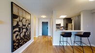 Located at 150 W Saint Charles Rd in Lombard, Illinois, this single-floor residence offers a thoughtfully designed open-concept layout with modern finishes throughout. Warm wood-tone flooring flows through the main living areas, creating a cohesive and inviting atmosphere from entry to living room.

The entryway welcomes you with a bold decorative accent wall and leads directly to the kitchen, which features dark wood cabinetry, stainless steel appliances including a refrigerator, range, and microwave, as well as a white quartz-topped peninsula with bar seating — ideal for casual dining or entertaining.

The living room is bright and airy, anchored by large sliding glass doors that open to a private balcony with outdoor views of the surrounding Lombard neighborhood. This seamless indoor-outdoor connection allows for generous natural light throughout the day.

The bedroom is a calm retreat with plush carpeting, a broad window framing outdoor views, and ample space for furnishings. The bathroom is clean and functional, complete with a tub-shower combination and light quartz countertops.

Throughout the residence, neutral tones and modern design elements contribute to a polished, move-in-ready aesthetic suited for comfortable everyday living in the heart of Lombard.
