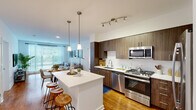 Located at 109 Commerce Dr in Exton, PA, this well-appointed 2-bedroom, 2-bathroom residence offers a thoughtfully designed single-level floor plan. The open-concept kitchen and living area serves as the heart of the home, featuring rich dark wood cabinetry, white quartz countertops, a subway tile backsplash, and a full suite of stainless steel appliances including a gas range, built-in microwave, dishwasher, and french door refrigerator. A central island with pendant lighting provides additional seating and workspace, while warm hardwood flooring flows throughout the main living areas. The living room is bright and inviting, with large sliding windows that frame outdoor views and fill the space with natural light. Both bedrooms are carpeted and generously sized, each featuring large windows with outdoor views and dedicated closets. The primary bathroom is finished with light wood vanity cabinetry, a white quartz countertop, and a glass-enclosed shower-tub combination. The second bathroom mirrors the clean, modern aesthetic with a wood vanity and a tub-shower combination. Two additional closets provide ample storage throughout. The overall design is clean and contemporary, with a neutral palette and modern finishes creating a bright, cohesive ambiance throughout.