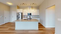 Located at 2805 Clinton Ave in Cleveland's vibrant Ohio City neighborhood, this modern single-floor residence offers a thoughtfully designed open-concept layout with high-quality finishes throughout. The expansive living area is bathed in natural light through large windows with views of the surrounding cityscape, and features warm hardwood-style flooring that flows seamlessly through the main living spaces.

The contemporary kitchen is a standout feature, showcasing crisp white shaker cabinetry, a subway tile backsplash, and a generous center island with an undermount sink. Stainless steel appliances, including a French door refrigerator, built-in microwave, and range, complement the sleek countertops. Stylish pendant and track lighting adds a warm, modern ambiance.

The bedrooms are well-proportioned, carpeted for comfort, and each is equipped with large windows that invite abundant natural light and city views. The primary bathroom offers a dual-sink vanity with white cabinetry and a large mirror, while the secondary bathroom features a full tub-shower combination and wood-look flooring. Both bathrooms are finished with brushed nickel fixtures and neutral toned walls. The unit also includes access to an outdoor space via a glass door from the living area, extending the sense of openness.
