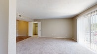 This single-story residence offers a well-organized layout across several rooms, each finished with a consistent palette of warm neutral tones and clean white trim. The spacious living area is carpeted and filled with natural light from a large sliding glass door fitted with vertical blinds, creating a bright and open atmosphere. A fireplace serves as a focal point, adding a functional and welcoming element to the main living space. Ceiling fans are present in the bedrooms, providing both comfort and circulation.

The kitchen features wood-look flooring, white cabinetry with brushed nickel hardware, granite-style countertops, and a stainless steel refrigerator. A dedicated laundry area with panel access is conveniently located nearby. The bedrooms are generously sized with plush carpeting and walk-in closets equipped with built-in shelving and hanging rods, offering ample storage.

The bathroom is well-appointed with a long vanity featuring grey countertops, white cabinetry, a large mirror, and a separate tub and shower area finished in white tile. Wood-look flooring extends through the bathroom, tying together the home's cohesive design. Textured ceilings are present throughout, and the overall layout reflects a practical and comfortable single-floor living arrangement.